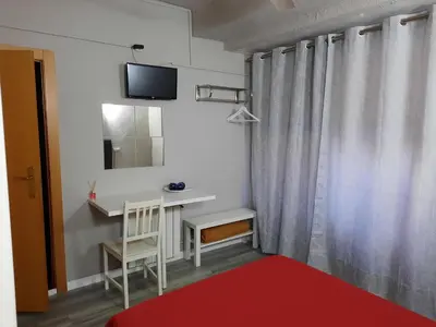 a bedroom with a bed with a red blanket and a window at Pensión Jamaica in Valencia
