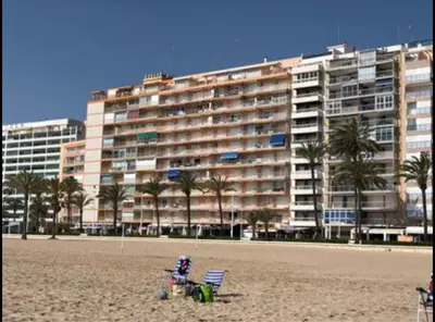 a large building on a beach with a chair and a building at Frente al mar in Cullera