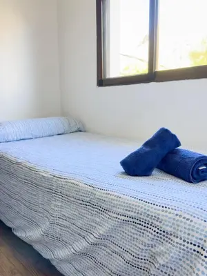 a bed with two blue sheets and a window at Apartamento Los Narcisos 2 in Chulilla