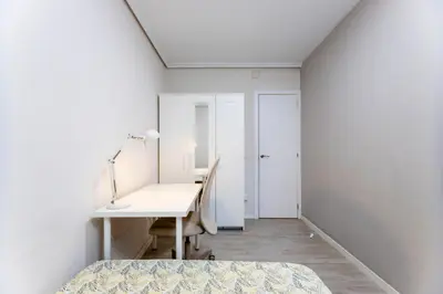 a white room with a desk and a bed and a table at Acogedor apartamento en Valencia cerca de la playa in Valencia