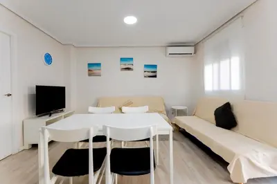 a living room with a white table and a couch at Acogedor apartamento en Valencia cerca de la playa in Valencia