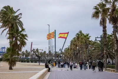 a group of people walking down a street with two flags at Acogedor apartamento en Valencia cerca de la playa in Valencia