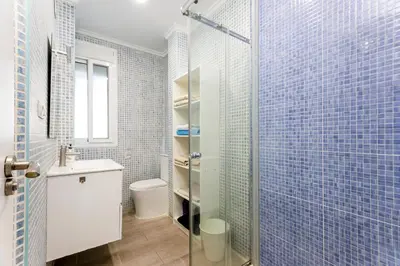a bathroom with a toilet and a shower with blue tiles at Acogedor apartamento en Valencia cerca de la playa in Valencia