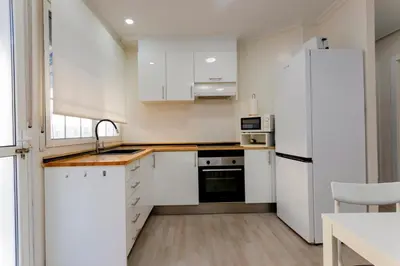 a kitchen with white cabinets and a white refrigerator at Acogedor apartamento en Valencia cerca de la playa in Valencia
