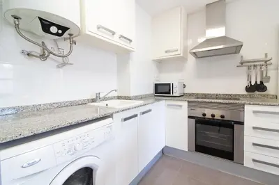 a white kitchen with a sink and a microwave at Global Vacacional, Bonito apartamento en Puerto Sagunto para parejas in Puerto de Sagunto