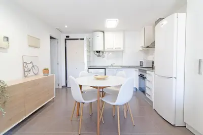 a kitchen with white appliances and a white table and chairs at Global Vacacional, Bonito apartamento en Puerto Sagunto para parejas in Puerto de Sagunto
