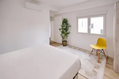 a bedroom with a white bed and a yellow chair at Carmen flat in Valencia