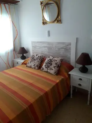 a bedroom with a bed with two lamps and a mirror at Apartamento Cullera a 200 metros playa San Antonio con parking in Cullera
