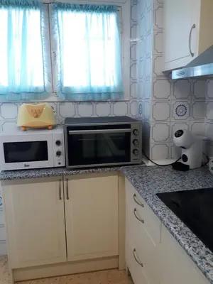 a kitchen with white cabinets and a microwave at Apartamento Cullera a 200 metros playa San Antonio con parking in Cullera