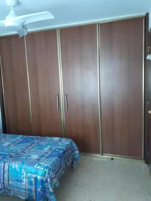a bedroom with a bed and wooden cabinets at Apartamento Cullera a 200 metros playa San Antonio con parking in Cullera