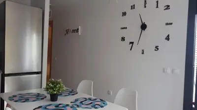 a white table with chairs and a clock on the wall at Neo Mediterráneo in Barrio-Mar