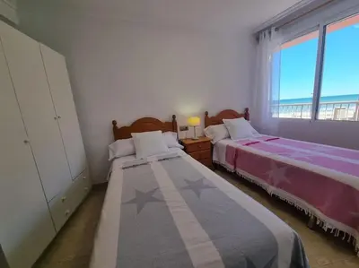 a bedroom with two beds and a large window at Apartamento en primera línea, Les Palmeretes in Sueca