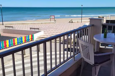 a balcony with a table and a view of the beach at Apartamento en primera línea, Les Palmeretes in Sueca