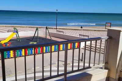 a playground on the beach next to the ocean at Apartamento en primera línea, Les Palmeretes in Sueca