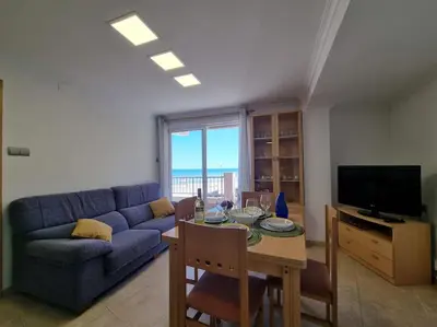 a living room with a blue couch and a table at Apartamento en primera línea, Les Palmeretes in Sueca