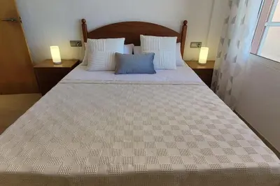 a large bed in a bedroom with two lamps at Apartamento en primera línea, Les Palmeretes in Sueca