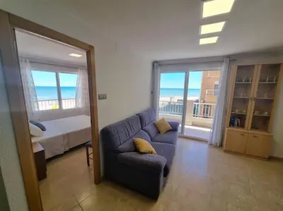 a living room with a couch and a bedroom at Apartamento en primera línea, Les Palmeretes in Sueca