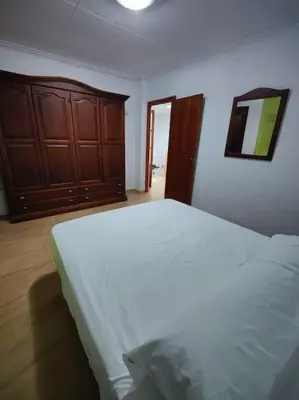 a bedroom with a white bed and a wooden cabinet at Casa de pueblo grande para 7 personas in Corbera de Alcira
