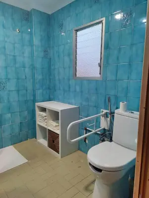 a blue tiled bathroom with a toilet and a window at Casa de pueblo grande para 7 personas in Corbera de Alcira
