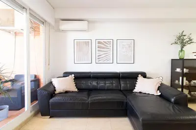 a black leather couch in a living room at Global Vacacional, Apartamento con piscina y terraza en la playa de Canet in Canet de Berenguer