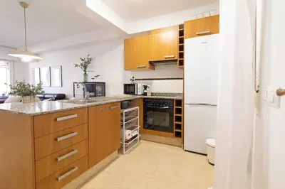 a kitchen with wooden cabinets and a white refrigerator at Global Vacacional, Apartamento con piscina y terraza en la playa de Canet in Canet de Berenguer