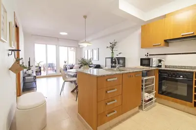 a kitchen with wooden cabinets and a counter top at Global Vacacional, Apartamento con piscina y terraza en la playa de Canet in Canet de Berenguer