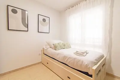 a bed in a room with a window at Global Vacacional, Apartamento con piscina y terraza en la playa de Canet in Canet de Berenguer