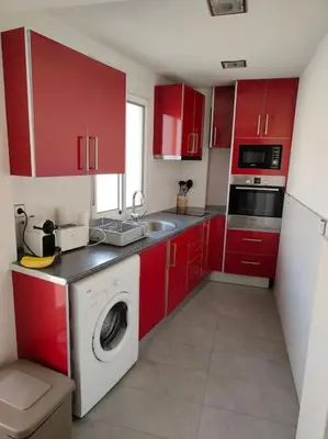a kitchen with red cabinets and a washing machine at Piso cerca universidades y playa in Valencia