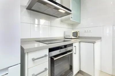 a white kitchen with a stove and a microwave at ApartUP Patacona Paradise Duplex in Valencia