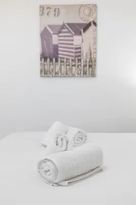 a stack of towels on a shelf with a picture at ApartUP Patacona Paradise Duplex in Valencia