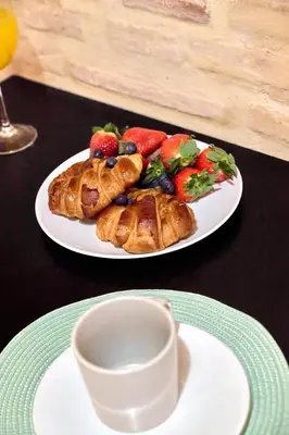 a plate of food with croissants and fruit on a table at Loft elegante en Plaza del Carmen F3 in Valencia