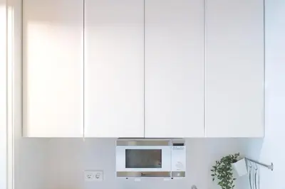 a microwave in a kitchen with white cabinets at Loft elegante en Plaza del Carmen F3 in Valencia