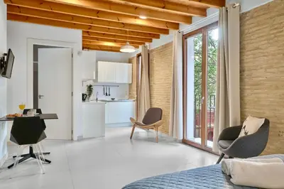 a room with a bed and chairs and a kitchen at Apartamento de diseño en Plaza del Carmen F4 in Valencia