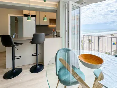 a kitchen and dining room with a glass table and chairs at El Séptimo Cielo de la Bahía de los Naranjos - Primera Línea de Playa in Cullera