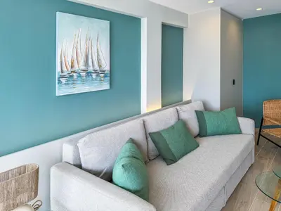 a living room with a couch and a painting of sailboats at El Séptimo Cielo de la Bahía de los Naranjos - Primera Línea de Playa in Cullera