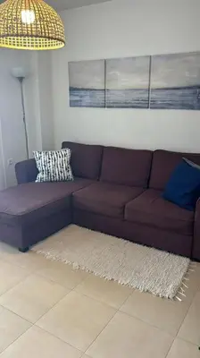 a living room with a purple couch and a lamp at Acogedor apartamento en la playa con WIFI y AACC in Moncófar