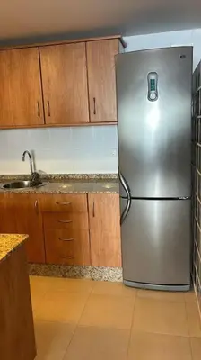 a stainless steel refrigerator in a kitchen with wooden cabinets at Acogedor apartamento en la playa con WIFI y AACC in Moncófar