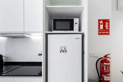 a refrigerator with a microwave on top of it at VLC HOST - San Jacinto in Valencia