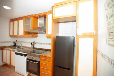 a kitchen with wooden cabinets and a black refrigerator at Precioso Apartamento en Valencia 2 dormitorios con Parking in Paterna