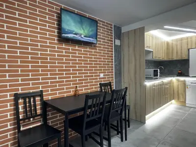 a kitchen with a table and chairs and a tv on a brick wall at Oriola 35 in Valencia