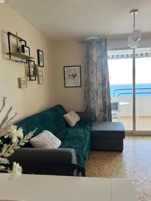 a living room with a green couch and a window at Apartamento en primera línea de la playa a 15 minutos de la Ciudad de Valencia in Valencia