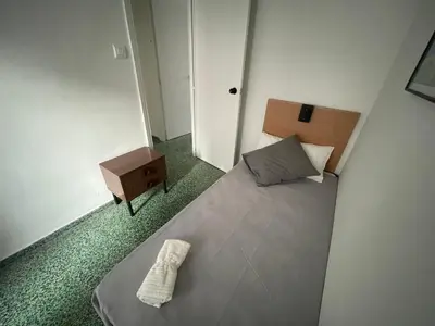 a small bedroom with a bed and a night stand at Luminoso piso cerca de la playa in Cullera