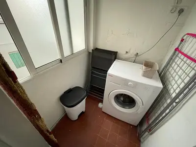 a small bathroom with a washing machine and a window at Luminoso piso cerca de la playa in Cullera