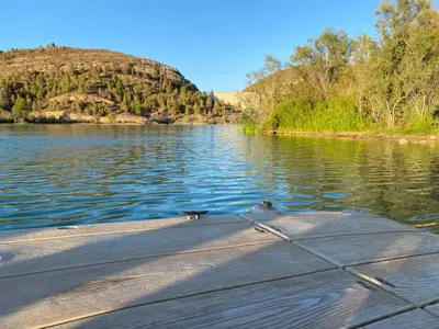 a dog sitting on the end of a boat on a lake at Casa the Dutchman in Navarrés