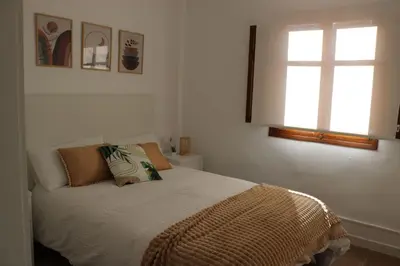 a bedroom with a bed and two windows at La Casa del Castell in Onda