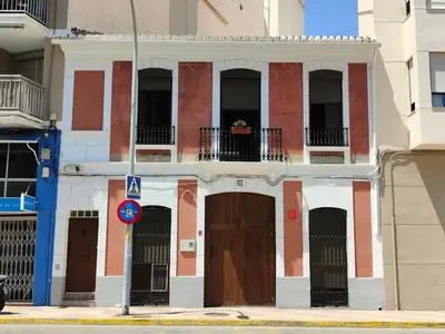 a red and white building with doors and windows at Casa Voramar in Cullera