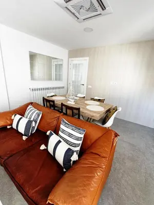 a brown leather couch in a living room with a table at Moderno Piso en Puerto Sagunto in Puerto de Sagunto