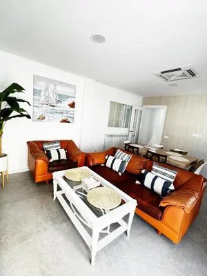 a living room with a leather couch and a table at Moderno Piso en Puerto Sagunto in Puerto de Sagunto