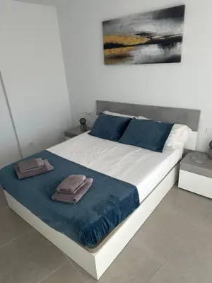 a white bed with blue sheets and pillows on it at Espectacular apartamento en Gran cannet in Canet de Berenguer