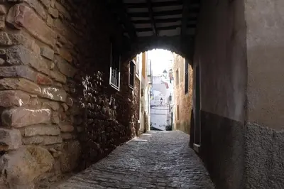 an alley way with an arch in a stone building at Casa rural Puchero y Manta in Alcudia de Veo